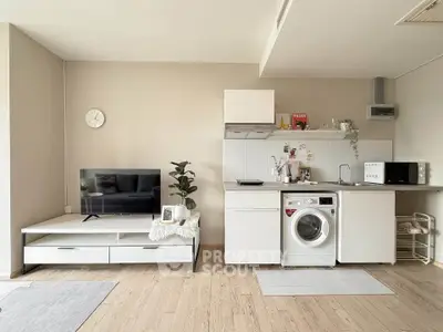 Modern open-plan living room with compact kitchen and washing machine, perfect for urban living.