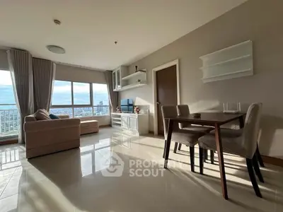 Spacious living room with large windows offering stunning city views, elegant furniture, and natural light.
