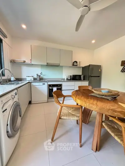 Modern kitchen with wooden dining set, washing machine, and stainless steel appliances.