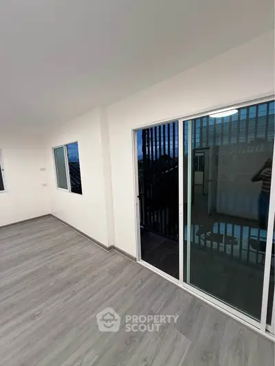 Spacious modern living room with sliding glass doors leading to a balcony, featuring sleek flooring and ample natural light.