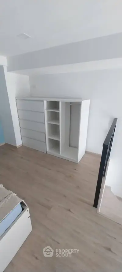 Modern bedroom with sleek white storage unit and wooden flooring