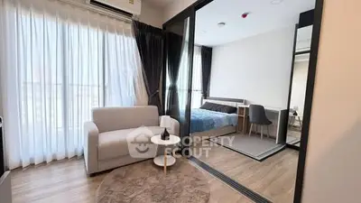 Modern studio apartment with cozy living area and stylish bedroom separated by glass partition.