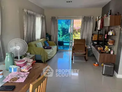 Cozy living room with modern decor and garden view, featuring a comfortable sofa and stylish shelving.