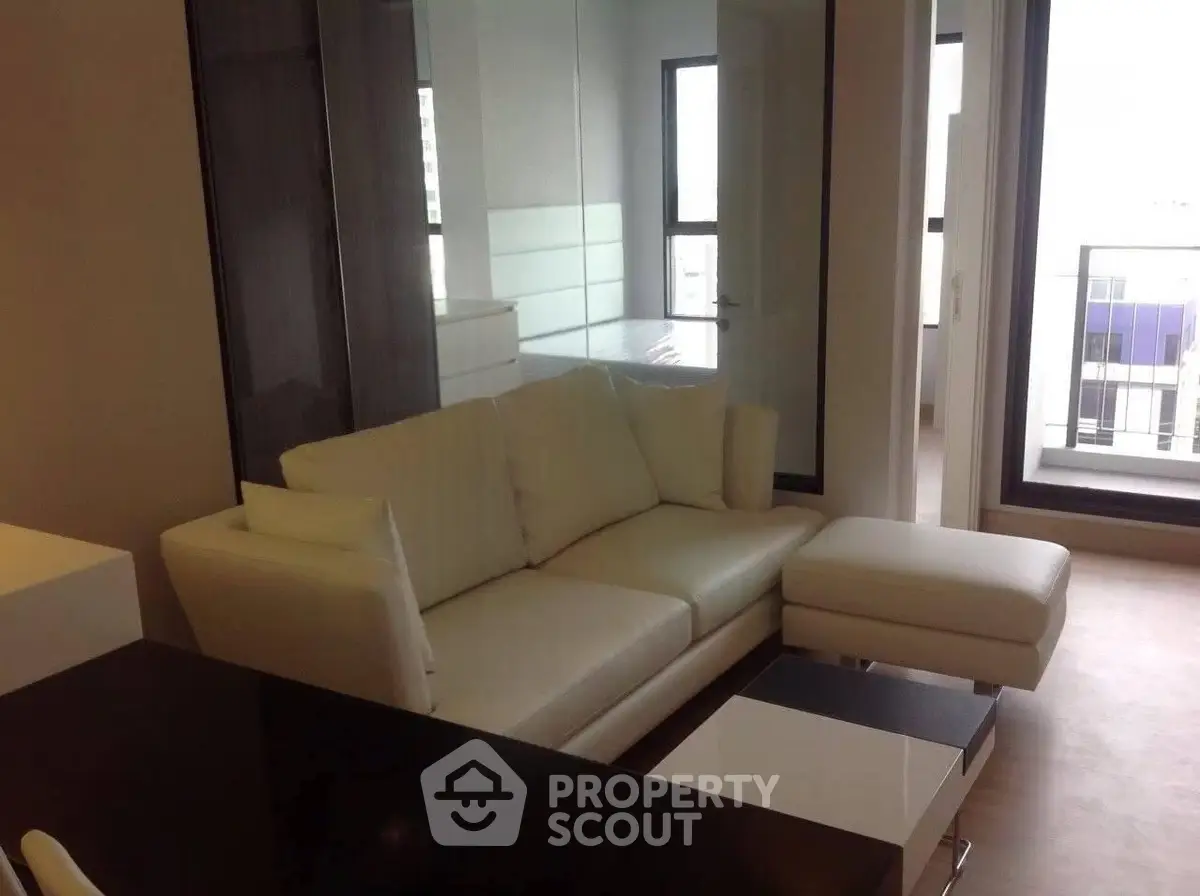 Modern living room with sleek white sofa and large windows offering natural light.