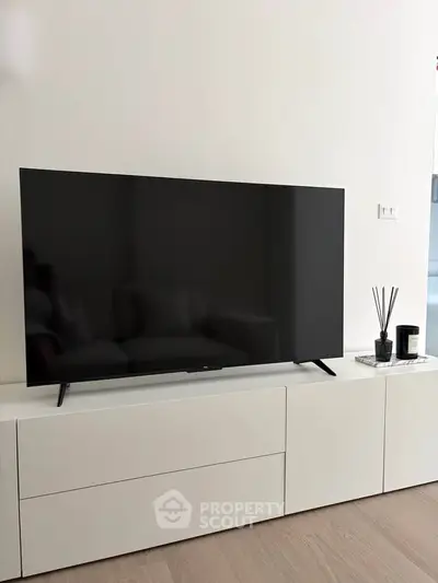 Modern living room with sleek TV on minimalist white cabinet, perfect for contemporary home entertainment.