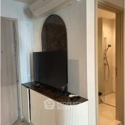 Modern living room with sleek TV setup and adjacent bathroom entrance