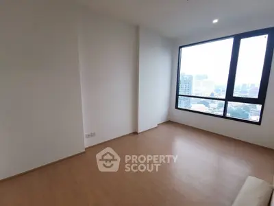 Spacious empty room with large window offering city views, perfect for customization.