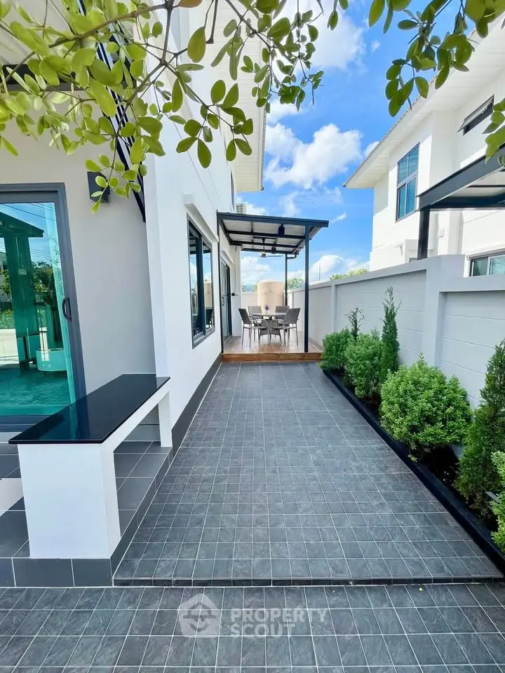 Modern outdoor patio with sleek tiles and lush greenery in a contemporary home setting.