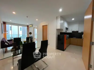 Modern open-plan living room and kitchen with sleek furnishings and balcony access.