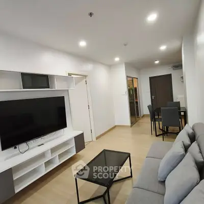 Modern living room with sleek furniture and large TV in a stylish apartment.