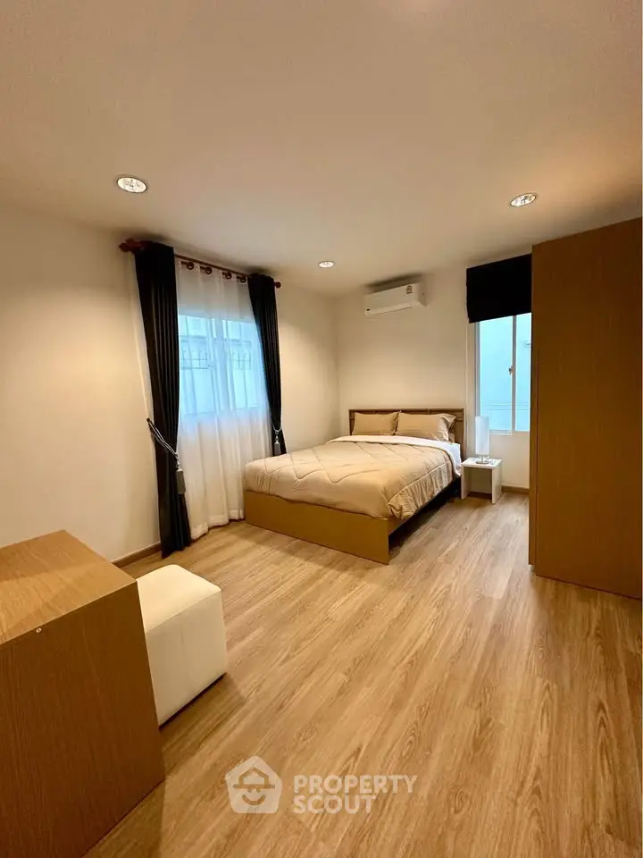 Spacious modern bedroom with wooden flooring and ample natural light