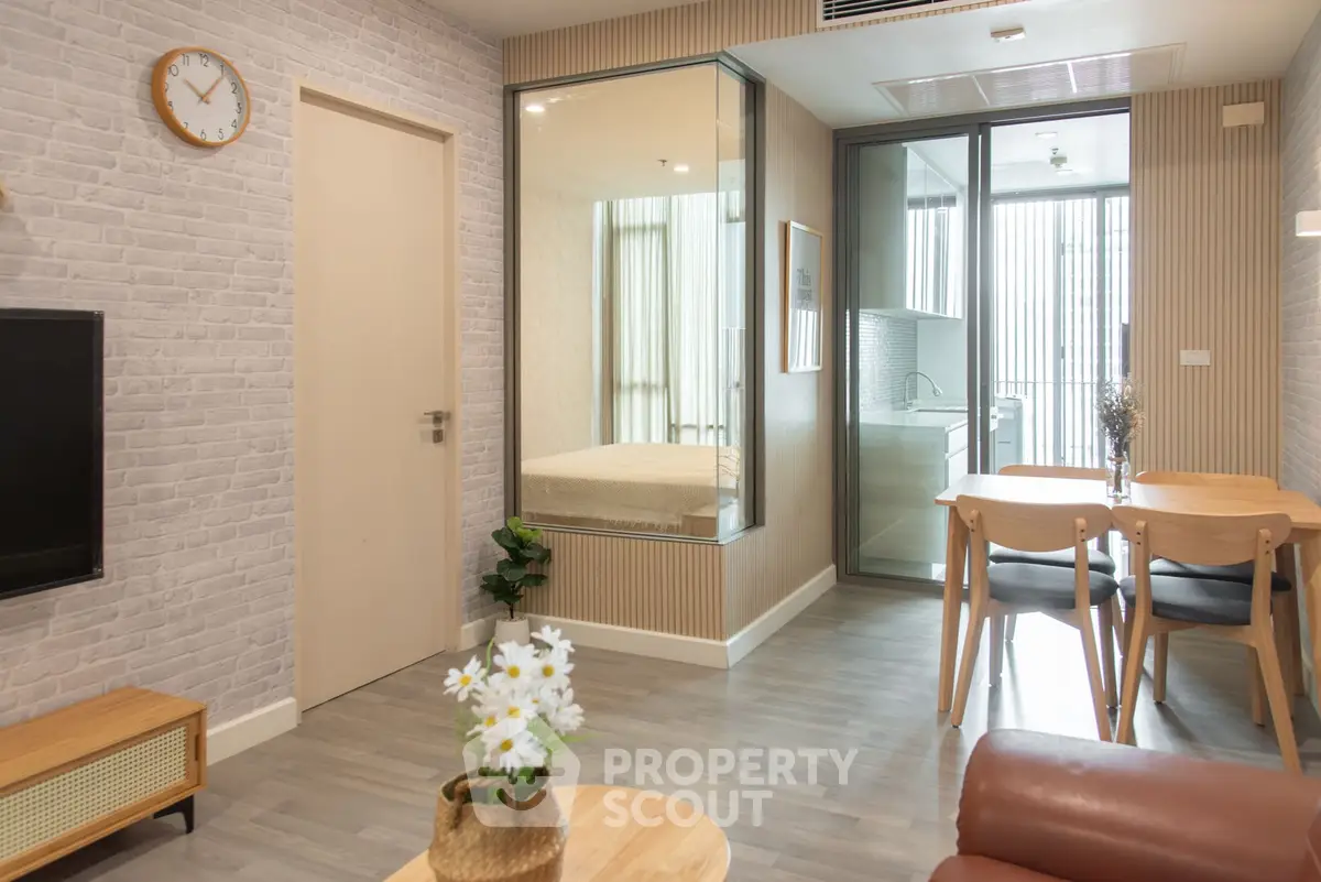 Modern living room with dining area and glass partition, featuring stylish decor and natural light.