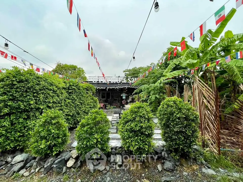 Charming garden view with lush greenery and festive flags, perfect for outdoor gatherings.