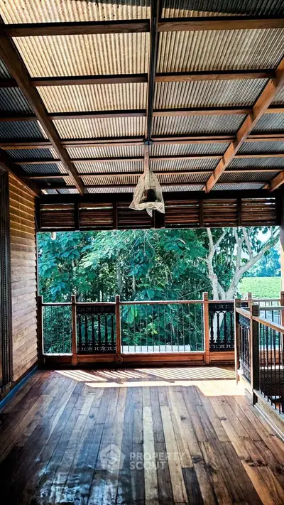 Charming wooden balcony with lush green view and rustic ceiling design.