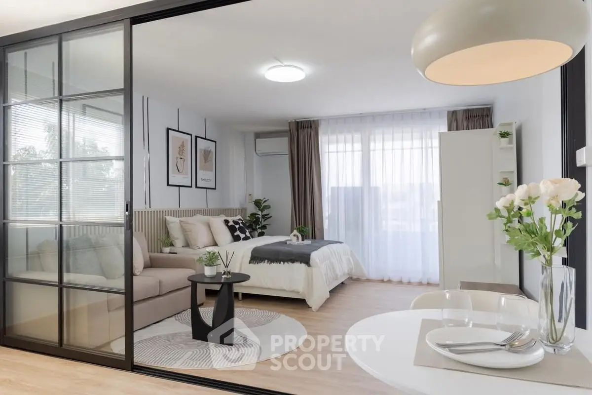 Modern studio apartment with open layout, featuring cozy living area and stylish bedroom separated by glass partition.