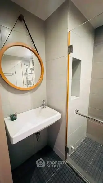 Modern bathroom with sleek design featuring a round mirror and glass shower enclosure.