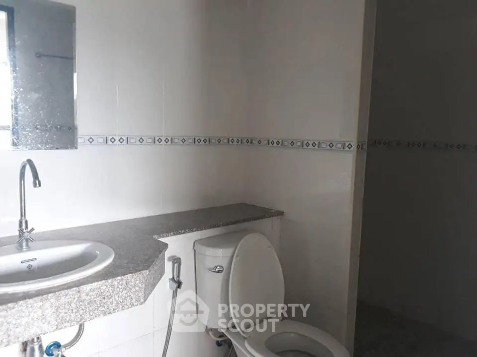 Modern bathroom with sleek granite countertop and white fixtures, featuring a stylish sink and toilet.