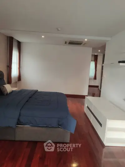 Spacious bedroom with elegant wooden flooring and modern furnishings.