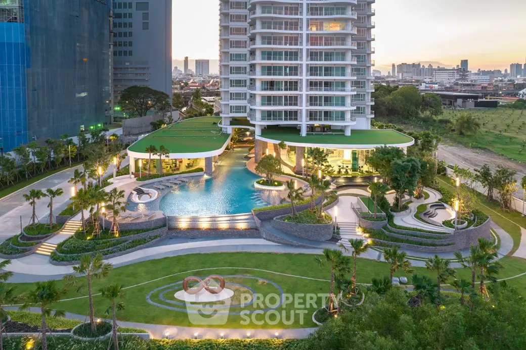 Luxurious high-rise building with stunning pool and landscaped gardens at sunset.