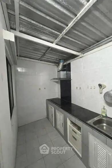 Compact kitchen with sleek countertops and stainless steel sink in modern home.