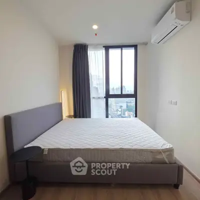 Modern bedroom with large window and city view, featuring a comfortable bed and sleek air conditioning unit.