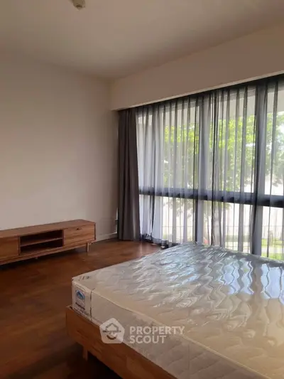 Spacious bedroom with large windows and wooden flooring