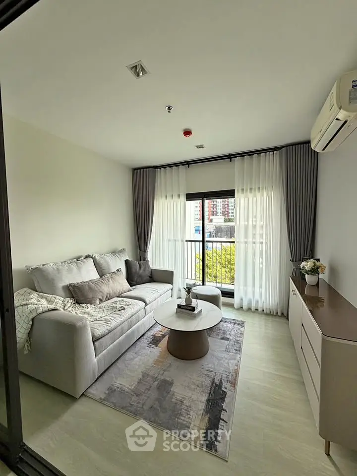 Modern living room with cozy sofa, stylish decor, and large window offering natural light.