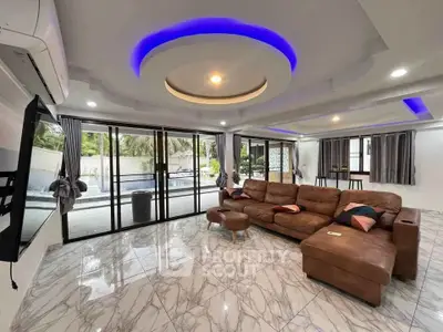 Luxurious living room with modern lighting and pool view, featuring sleek marble flooring and stylish leather sofa.