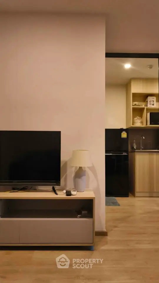 Modern living room with sleek TV stand and open kitchen layout, perfect for contemporary living.