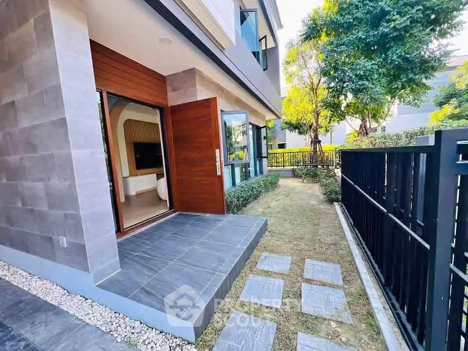 Modern home exterior with garden and patio, featuring sleek design and lush greenery.