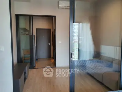 Modern apartment interior with glass partition, wooden flooring, and sleek furniture design.