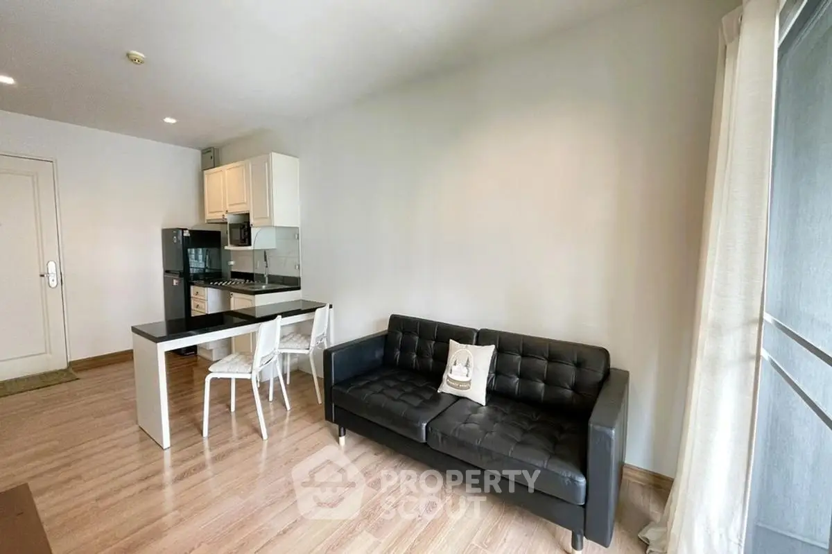 Modern open-layout living room with sleek black sofa and stylish kitchen area