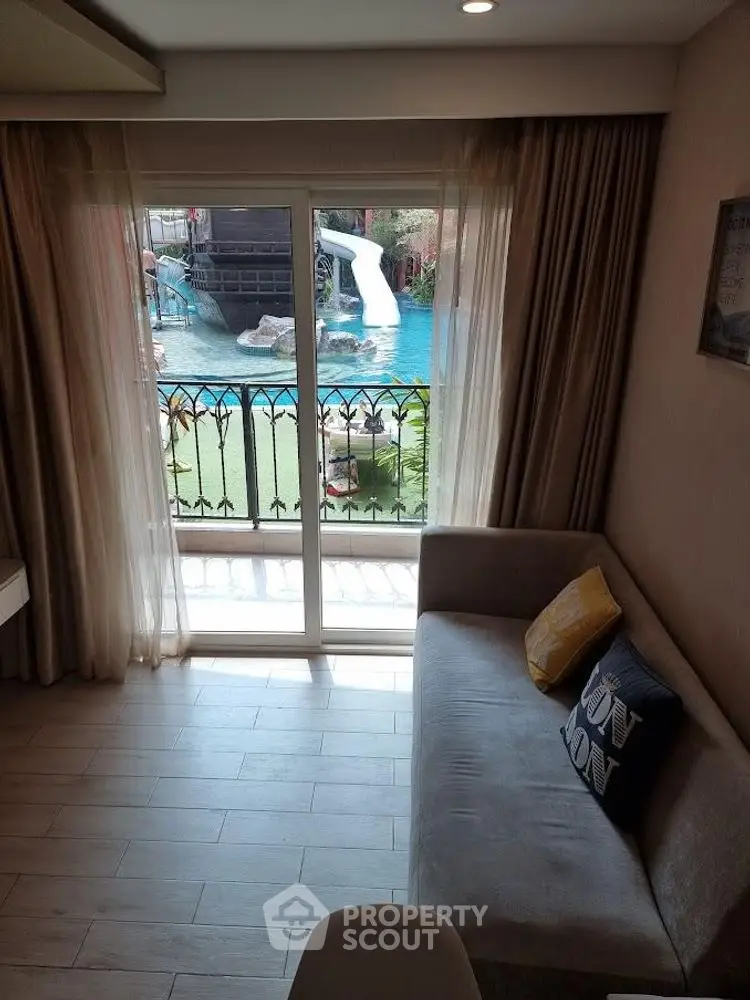 Cozy living room with pool view through glass doors, featuring a comfortable sofa.