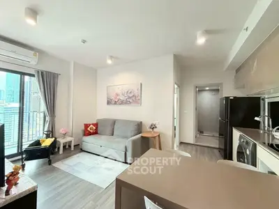 Modern living room with open kitchen in a high-rise apartment, featuring city views and stylish decor.