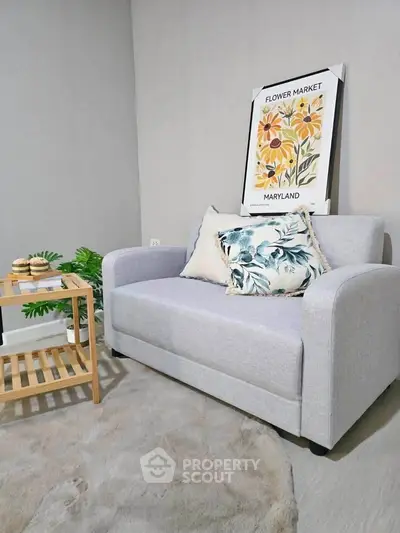 Cozy living room with a stylish gray sofa, floral artwork, and a chic wooden side table.