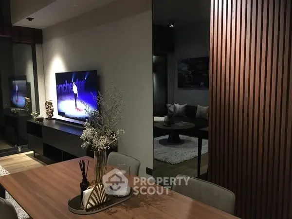 Modern living room with stylish decor and large TV, perfect for entertainment.