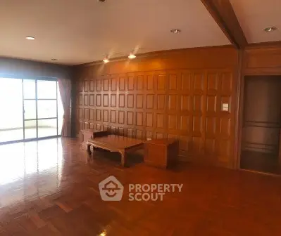 Spacious living room with wooden paneling and large windows for natural light.