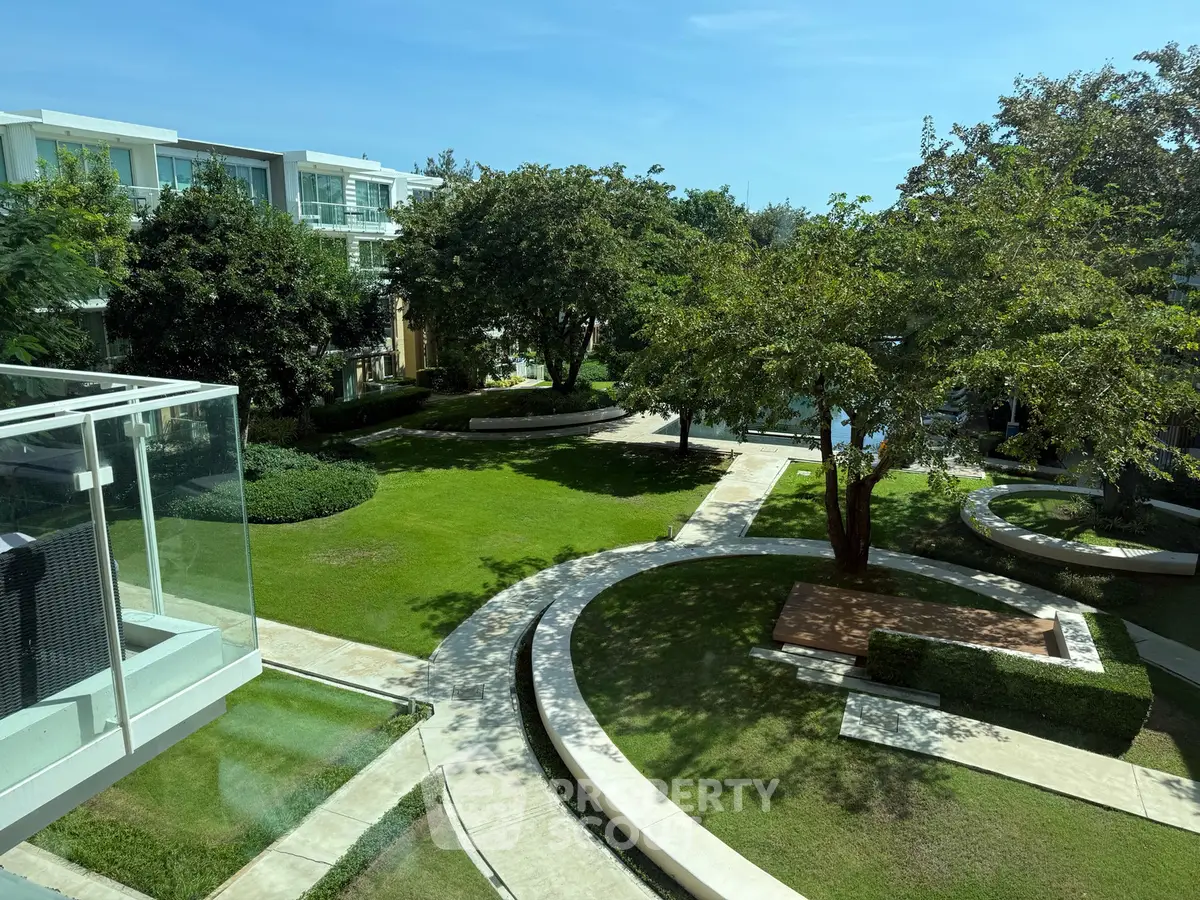 Luxurious garden view from modern apartment balcony with lush greenery and serene pathways.