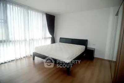 Spacious bedroom with large windows and modern furnishings in a stylish apartment.