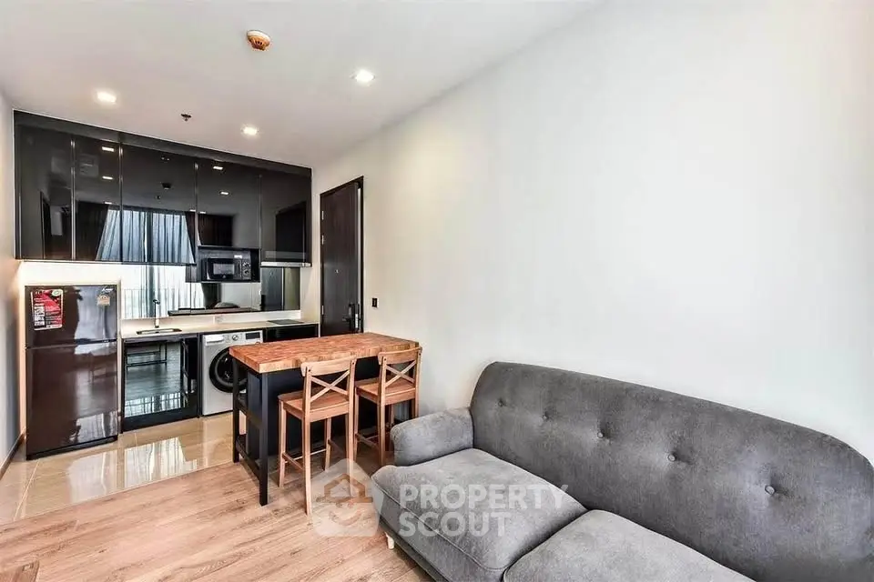 Modern living room with sleek kitchen, cozy sofa, and stylish dining area in open layout apartment.