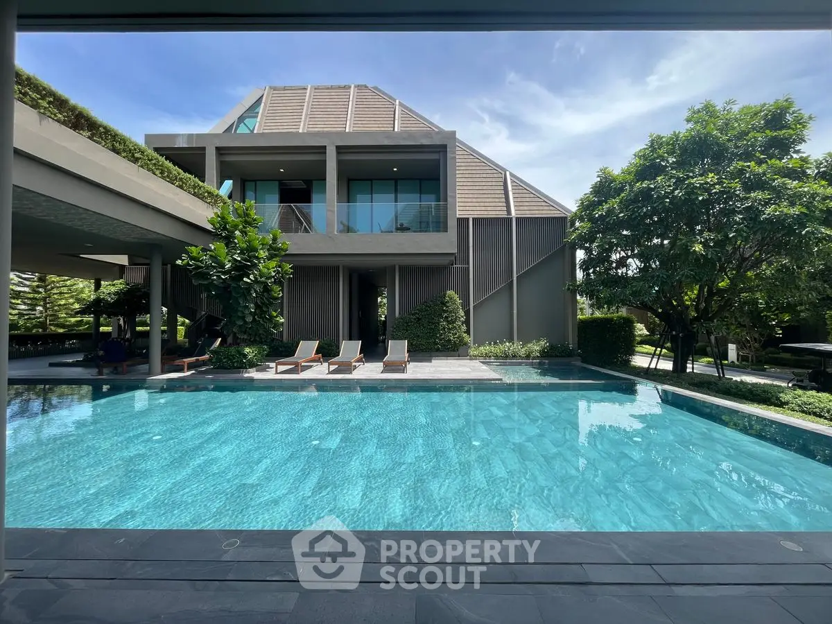 Luxurious modern home with stunning pool and lush greenery, perfect for relaxation and entertainment.
