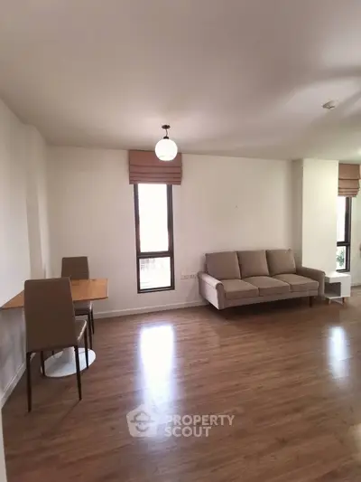 Spacious living room with modern furniture and wooden flooring, perfect for relaxation and entertaining.