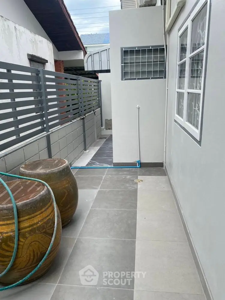 Modern exterior walkway with tiled flooring and decorative barrels