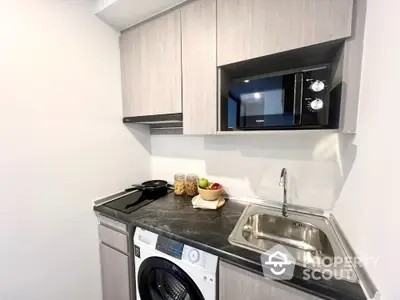 Modern compact kitchen with washing machine and microwave in sleek design