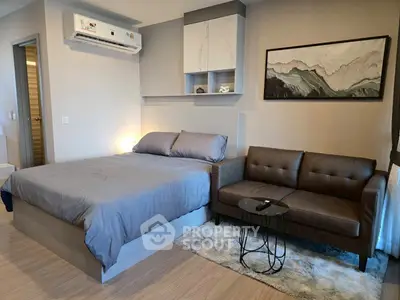 Modern studio apartment with cozy bed and stylish sofa in a well-lit room.