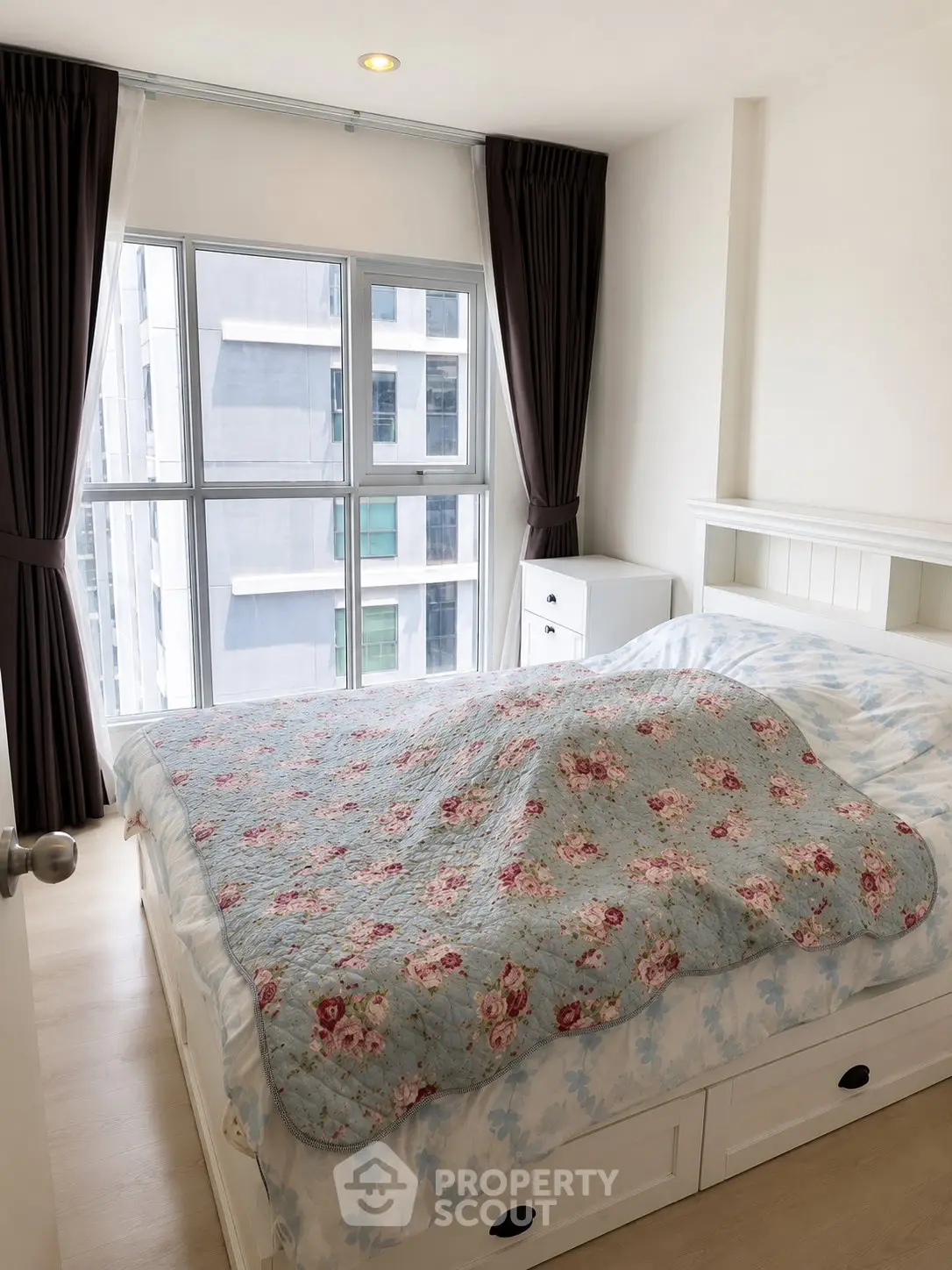 Cozy bedroom with large window and floral bedding in modern apartment