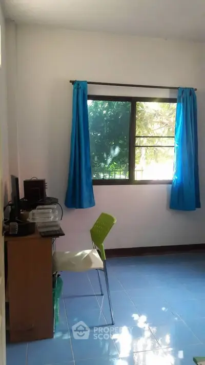 Bright study room with blue curtains and a window view, featuring a desk and chair.