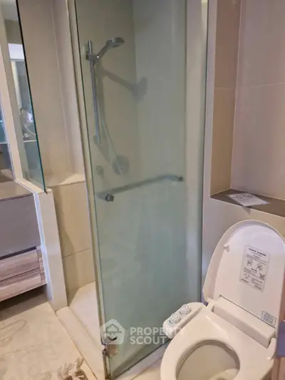 Modern bathroom with glass shower and smart toilet in luxury apartment.