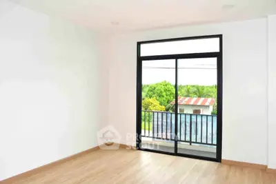 Bright empty room with large window and balcony overlooking lush greenery, perfect for modern living.
