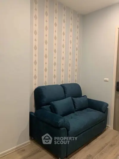 Cozy living room with stylish blue sofa and modern wallpaper accent wall.